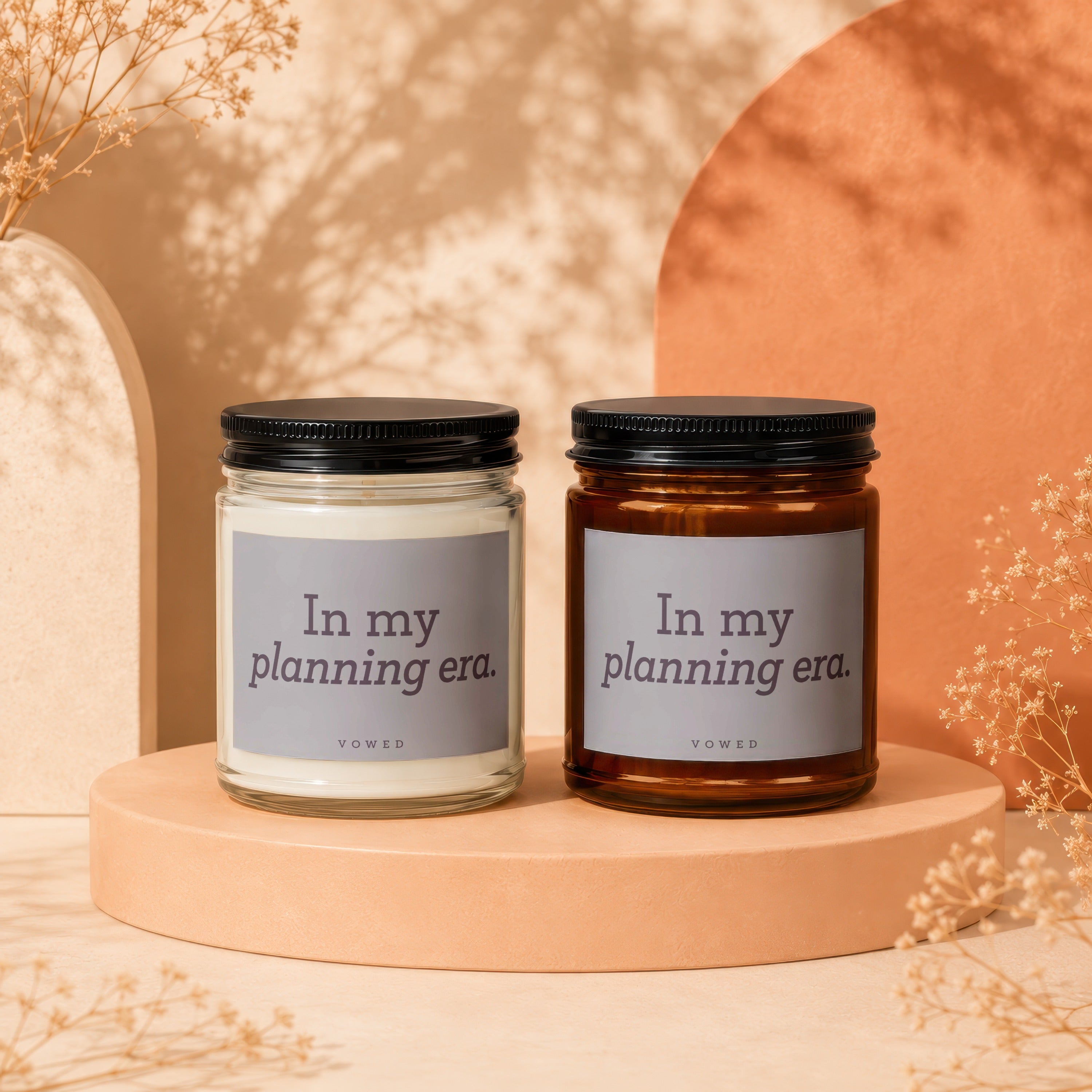 Two candles with "In my planning era." text on labels, set on display stands.