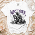 White t-shirt with "Monster Bride" graphic of Godzilla in a veil and sash.