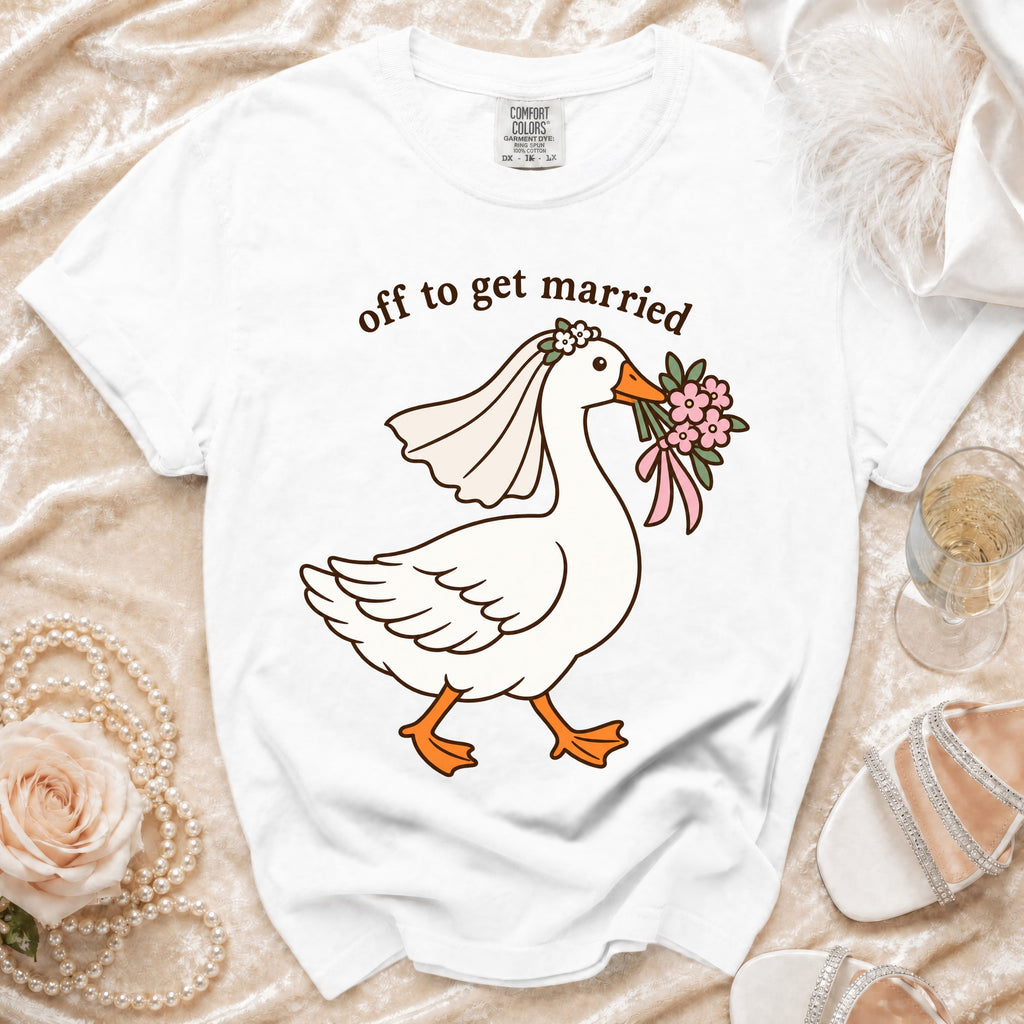 White t-shirt with cartoon goose wearing veil, holding flowers, and text "off to get married".