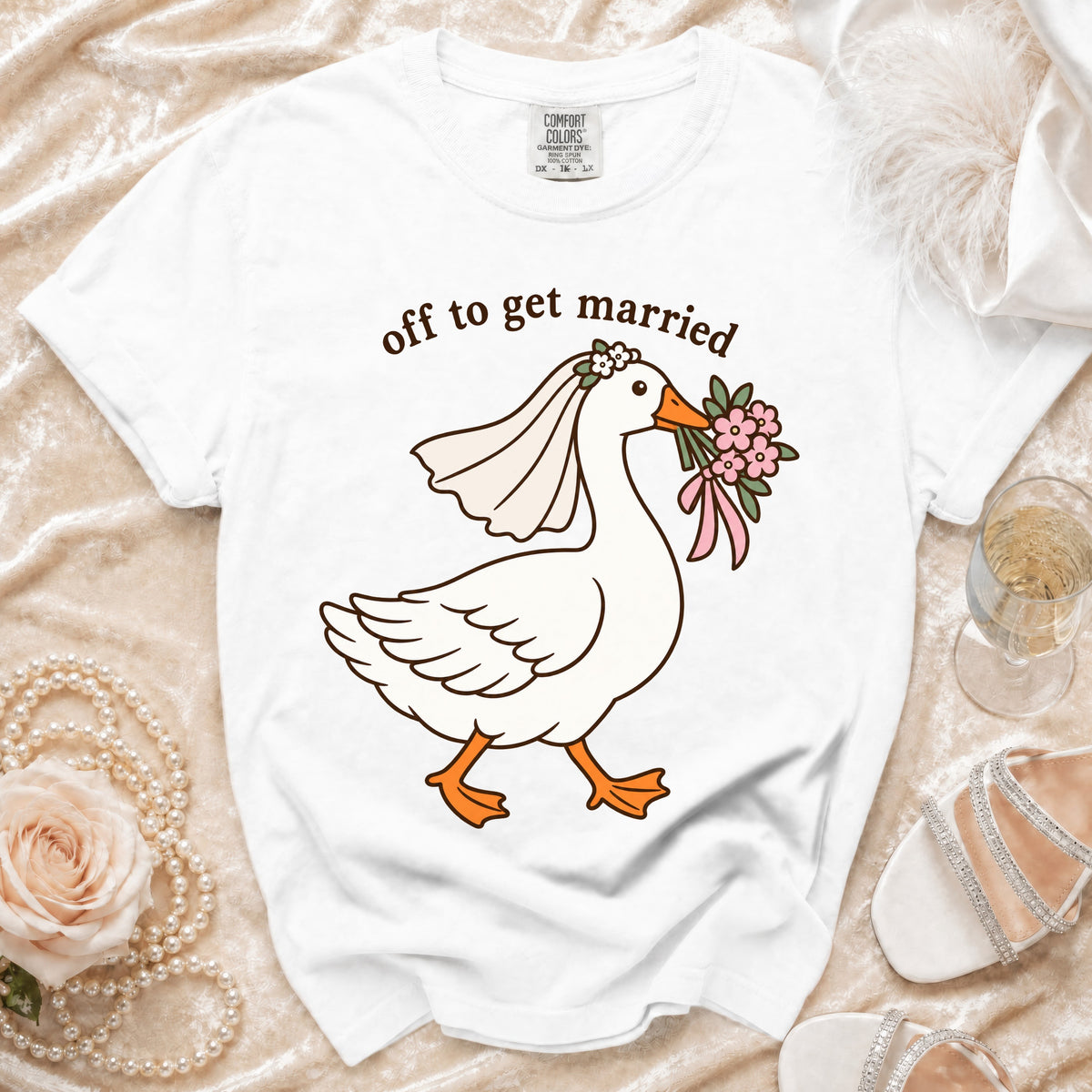 White t-shirt with cartoon goose wearing veil, holding flowers, and text "off to get married".