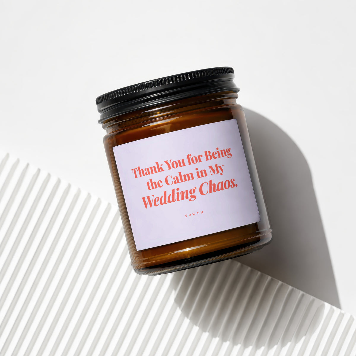 Amber glass candle with black lid, featuring a label that reads "Thank You for Being the Calm in My Wedding Chaos."