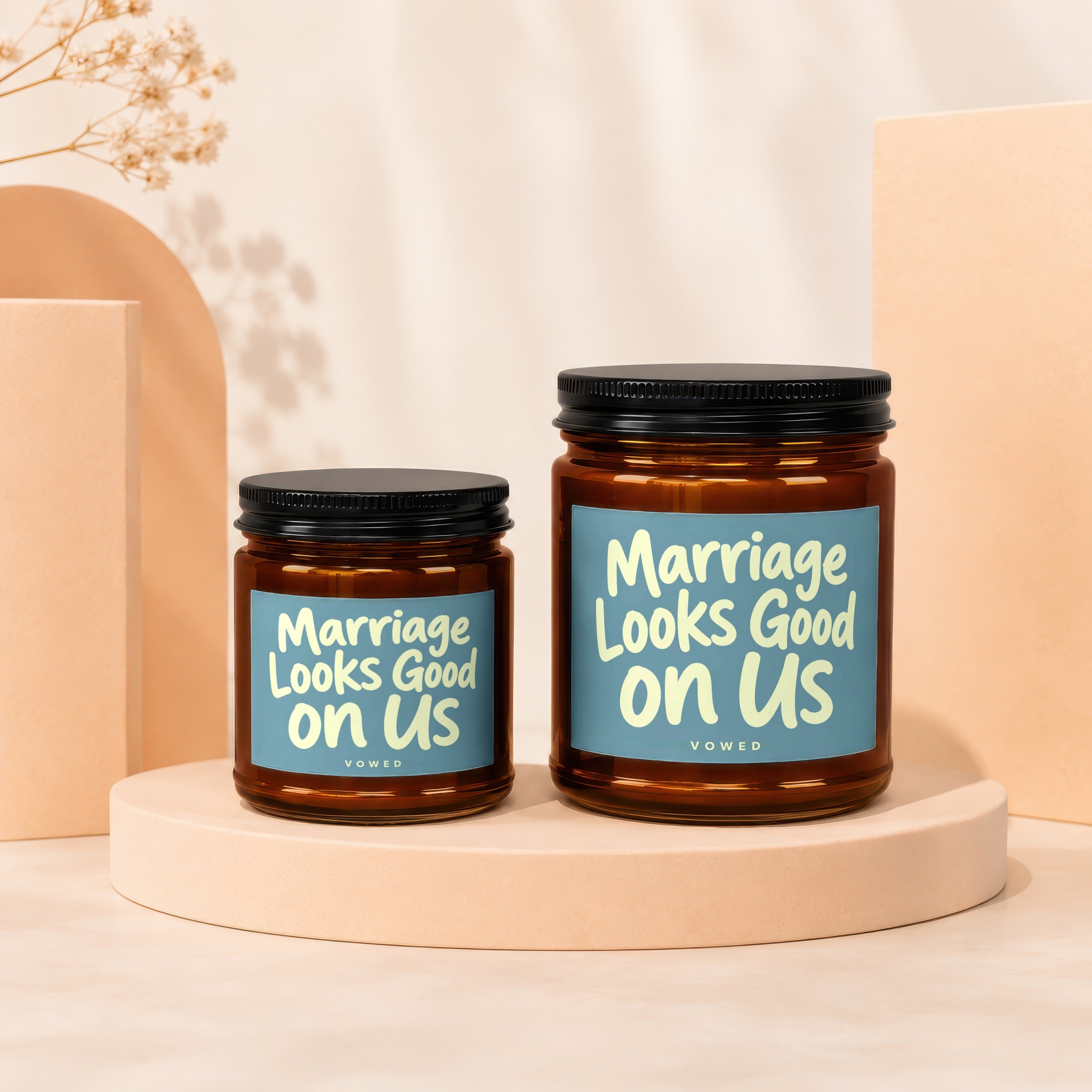 Two amber glass candles with black lids, labeled "Marriage Looks Good on Us".