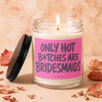 Glass candle with lit wick and pink label reading "ONLY HOT B*TCHES ARE BRIDESMAIDS".
