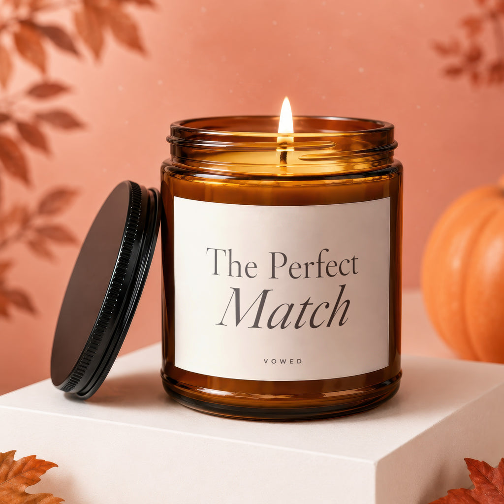 Amber jar candle with burning flame, displaying "The Perfect Match" and "VOWED" text.