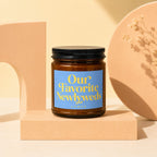 Amber glass candle with blue label reading "Our Favorite Newlyweds" by Vowed.