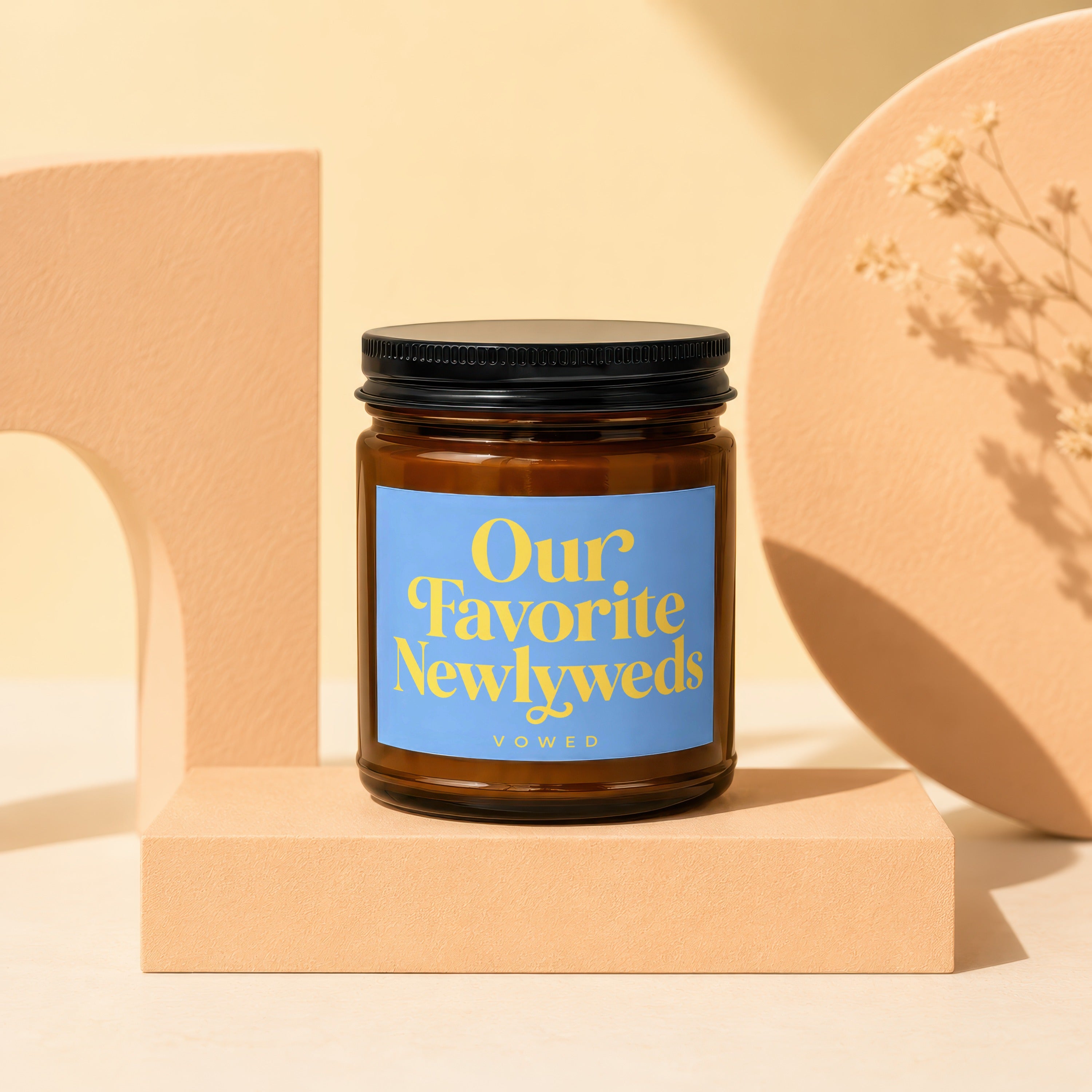 Amber glass candle with blue label reading "Our Favorite Newlyweds" by Vowed.