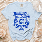 Light blue t-shirt with "Holding Her Dress and Her Secrets" graphic.