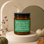 Candle with green label reading "Bouquet Catching Wasn't in My Job Description"