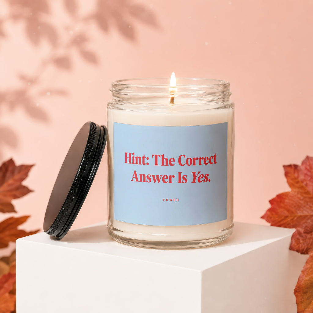 Glass jar candle with light blue label that reads "Hint: The Correct Answer Is Yes."