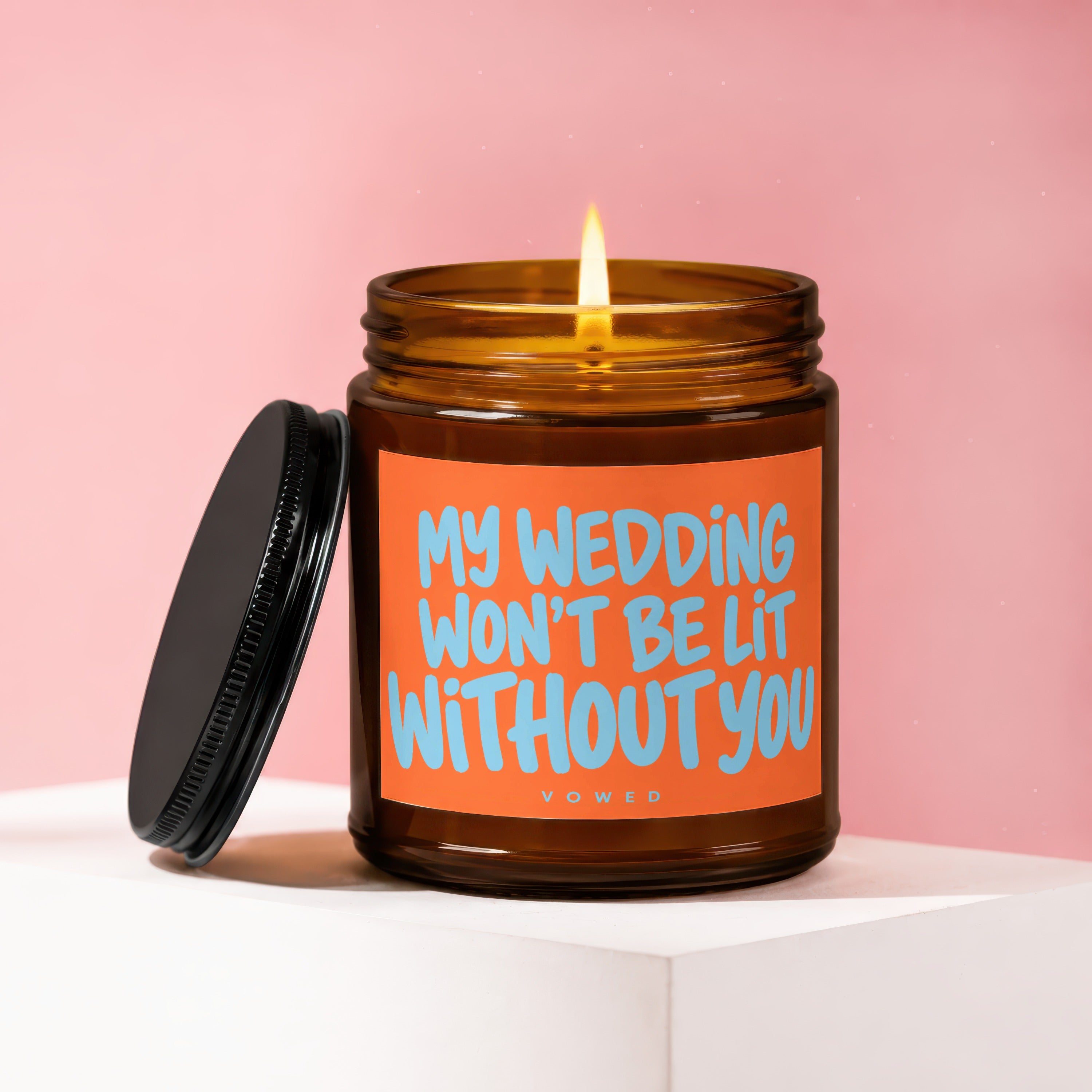 Amber candle with lit flame and orange label reading "MY WEDDING WON'T BE LIT WITHOUT YOU."