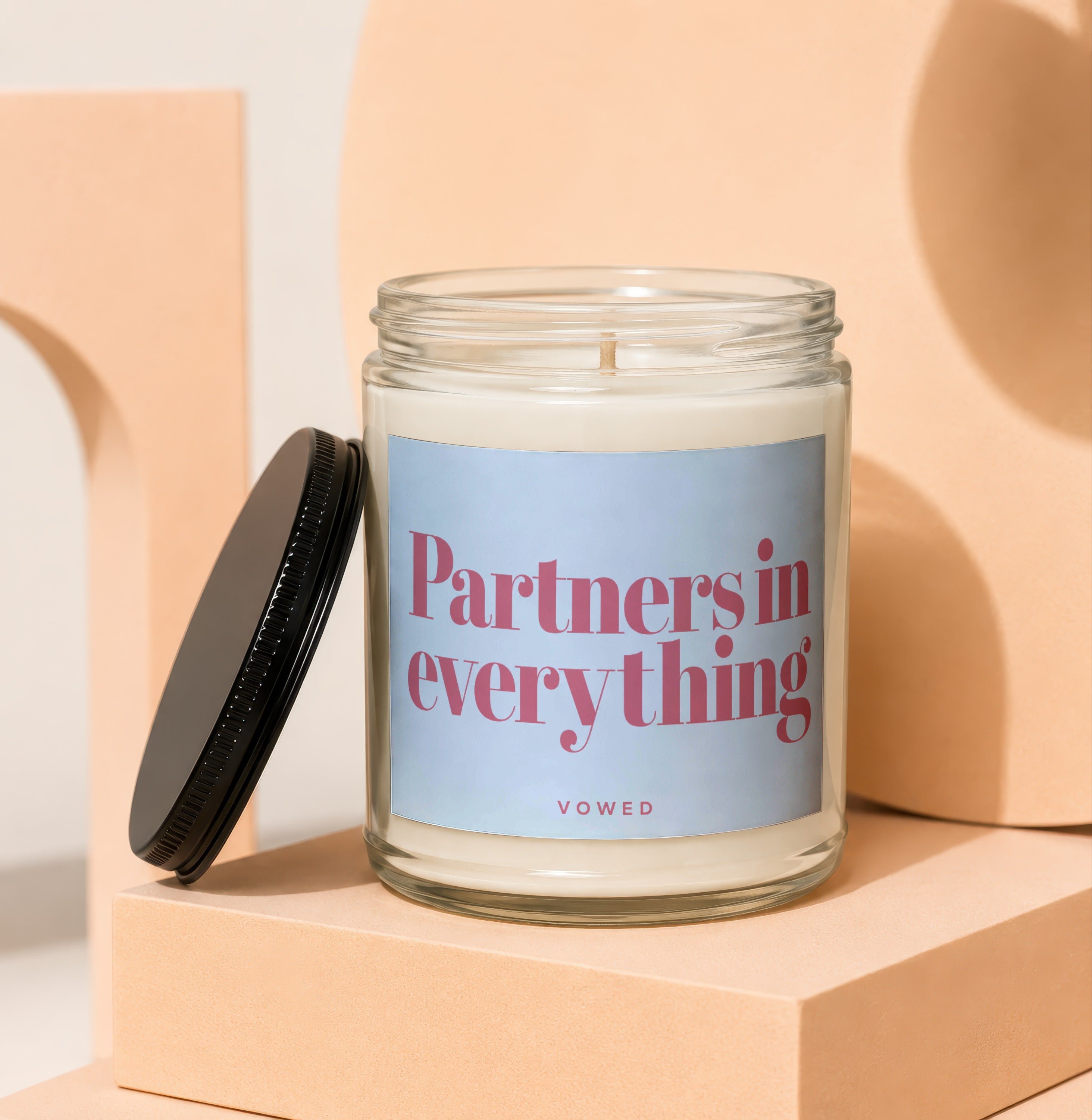 Glass jar candle with a black lid, featuring text "Partners in everything VOWED".