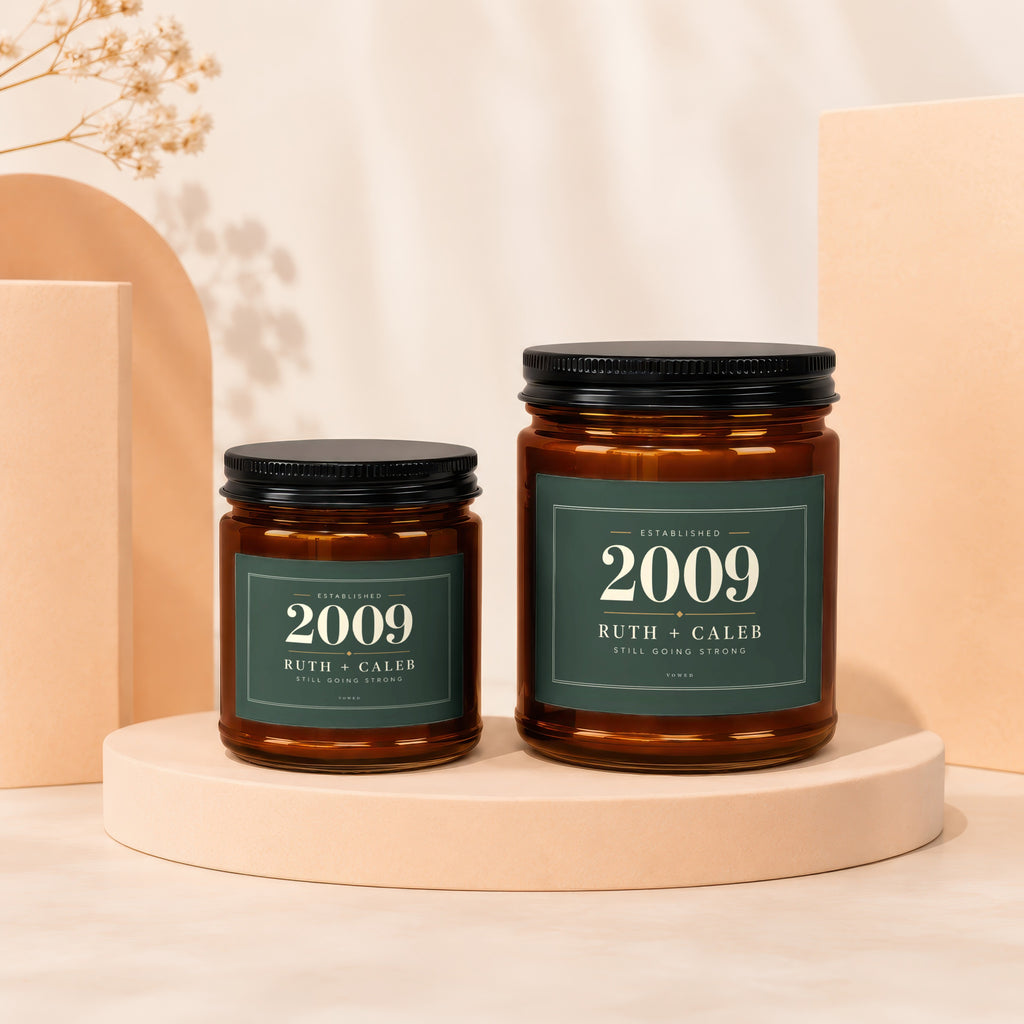 Two amber glass candles with green labels reading "Established 2009 Ruth + Caleb Still Going Strong".