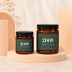 Two amber glass candles with green labels reading "Established 2009 Ruth + Caleb Still Going Strong".