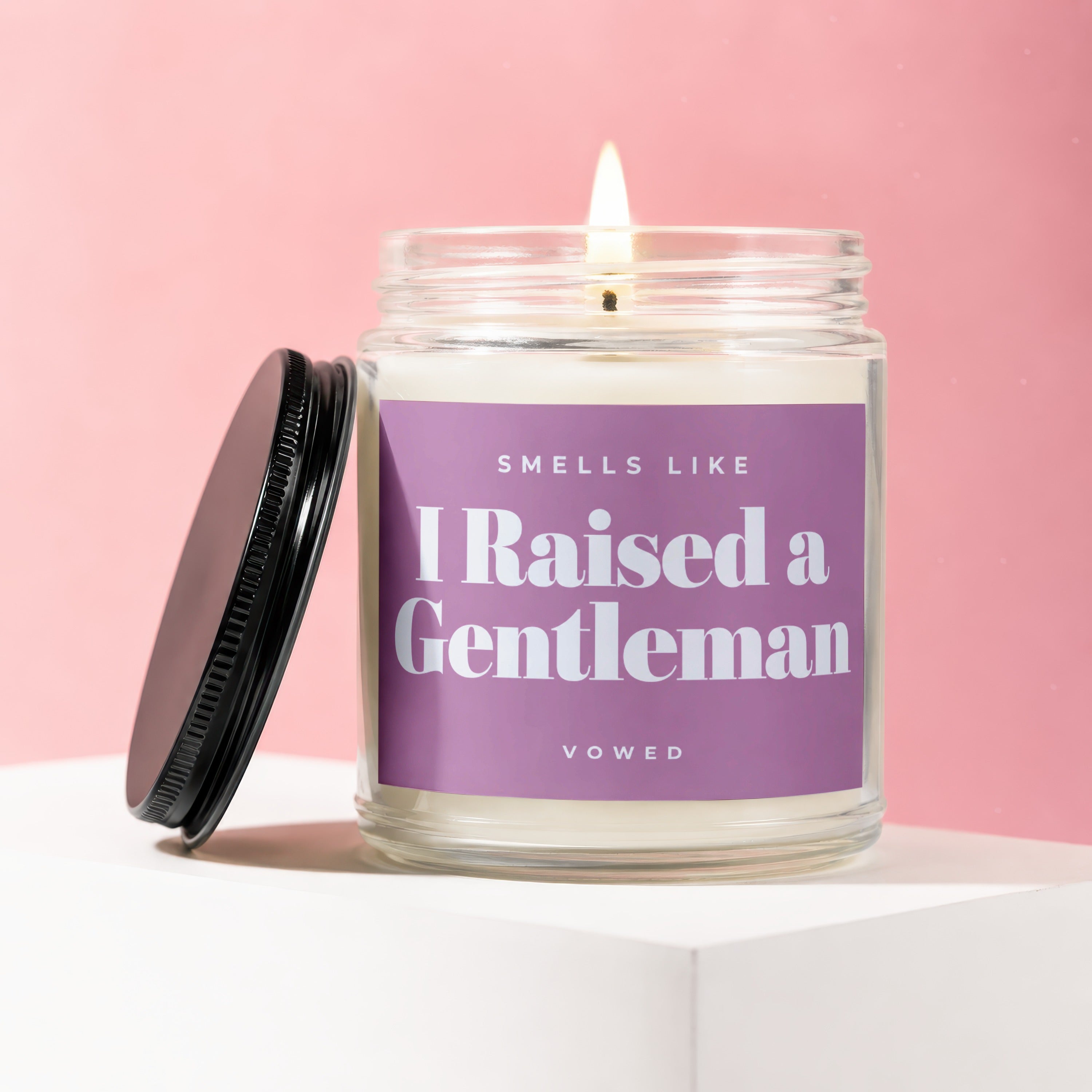 Scented candle in glass jar with purple label: "Smells Like I Raised a Gentleman"