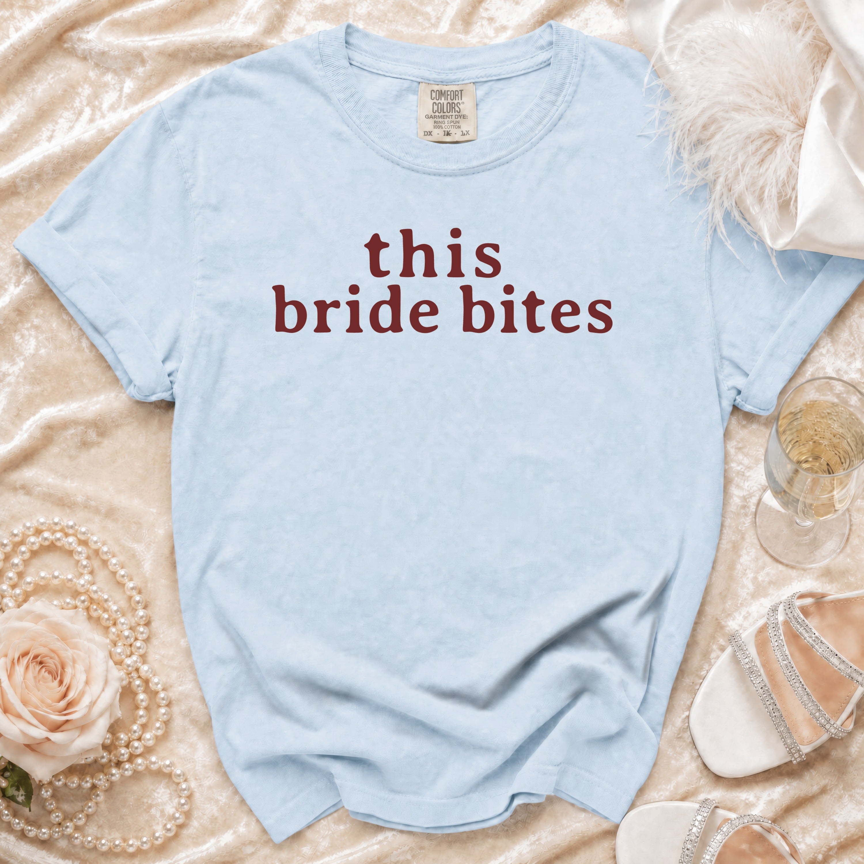 Light blue t-shirt with maroon text "this bride bites" and garment tag.