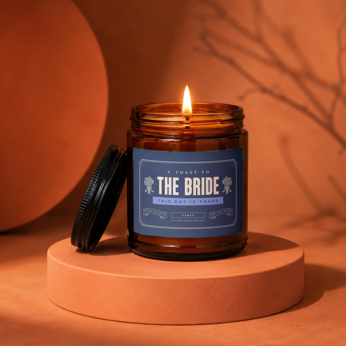 Amber glass candle with "The Bride" label, lit flame, lid off.