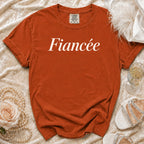 Orange t-shirt with "Fiancée" printed in white script, with wedding accessories.