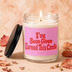Burning candle in glass jar with pink label reading "I've Earned This Candle"