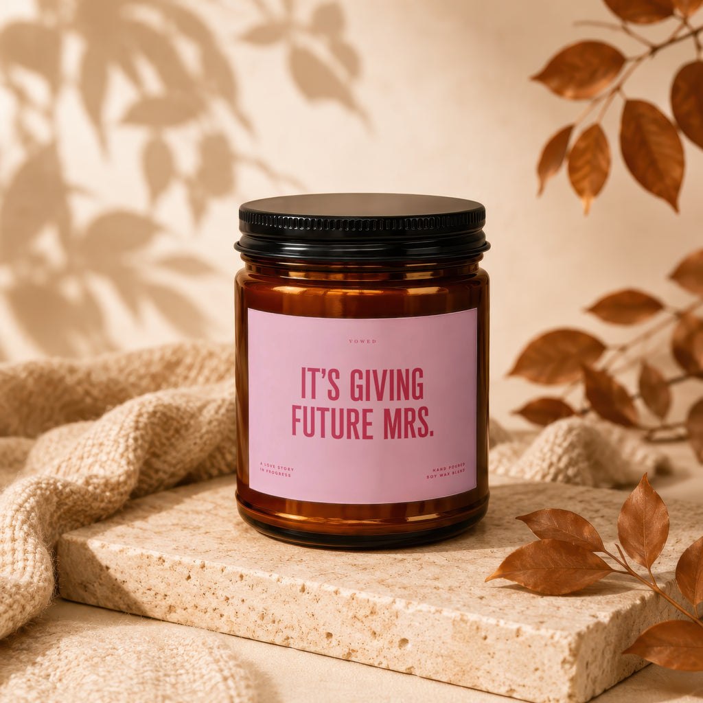 Amber candle with pink label saying "It's Giving Future Mrs."