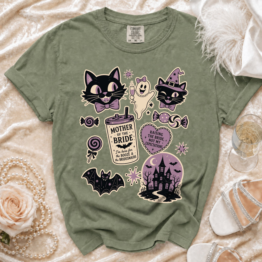 Sage green t-shirt with a vintage Halloween graphic featuring cats, a ghost, a haunted house, and text.