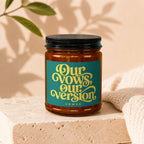 Amber jar candle with a teal label featuring yellow text "Our Vows, Our Version, Vowed".