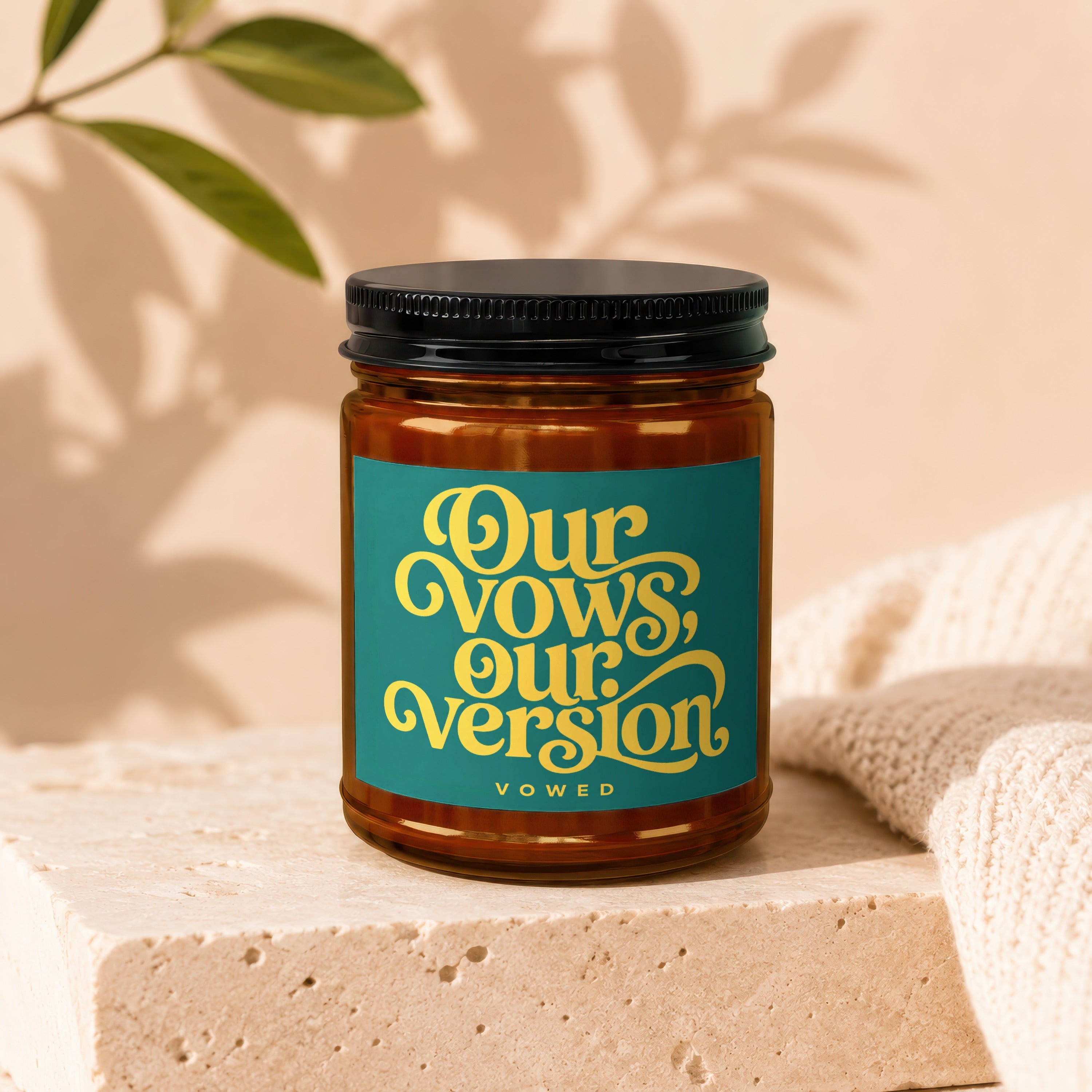 Amber jar candle with a teal label featuring yellow text "Our Vows, Our Version, Vowed".