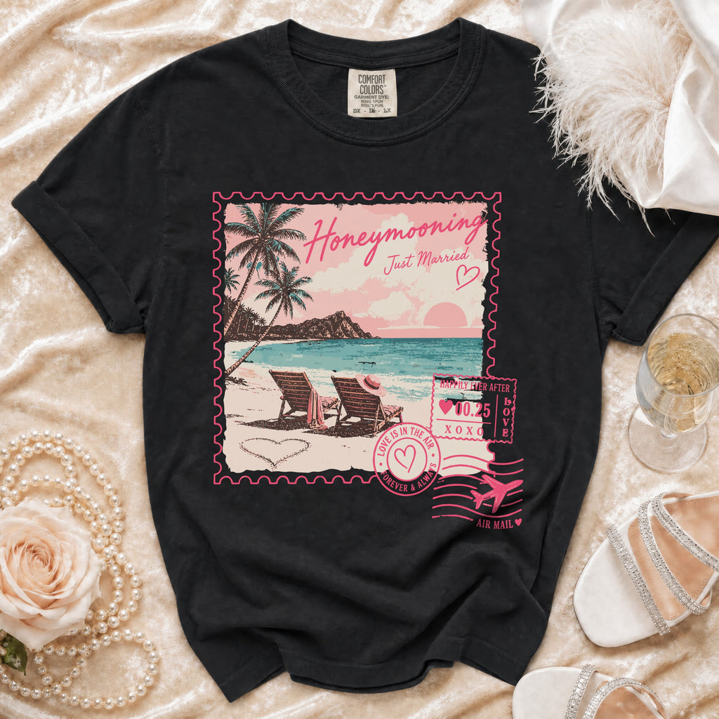Black t-shirt with "Honeymooning Just Married" tropical scene resembling a postcard stamp.