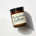 Brown glass candle with a cream label reading "The Newlywed Glow".