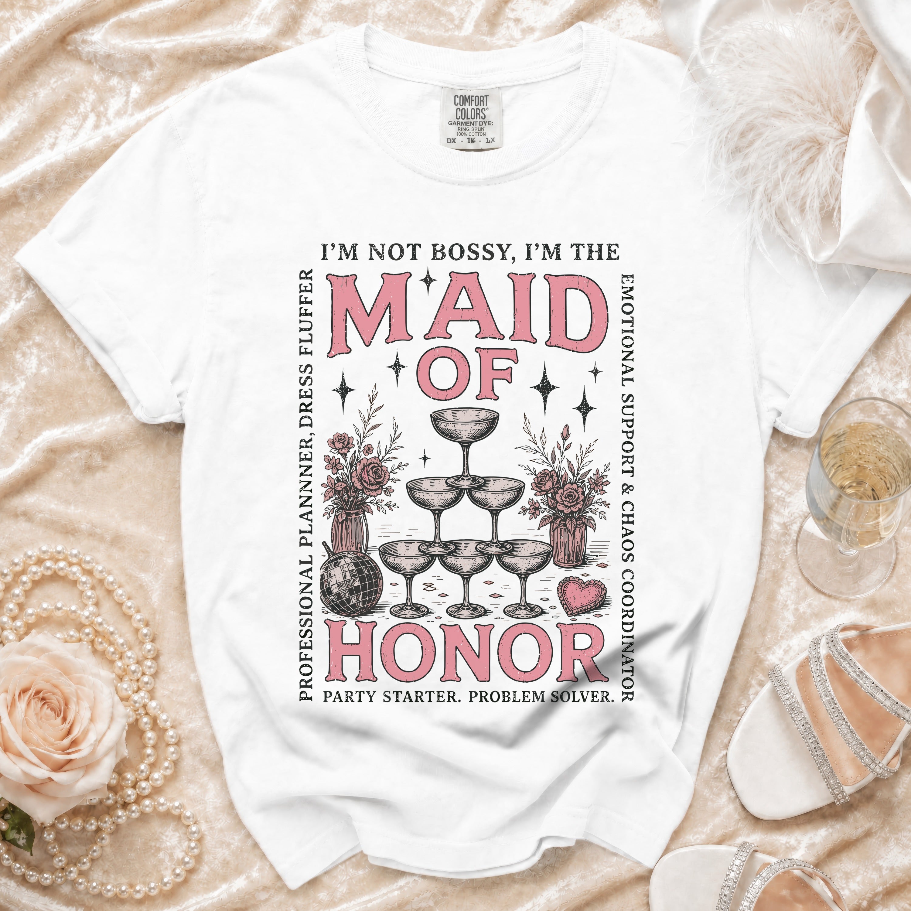 White t-shirt with "MAID OF HONOR" text, champagne glasses, and floral graphics.