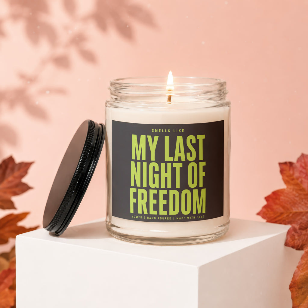Candle with "My Last Night of Freedom" text on label, lid removed, autumn leaves.