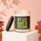 Candle with "My Last Night of Freedom" text on label, lid removed, autumn leaves.