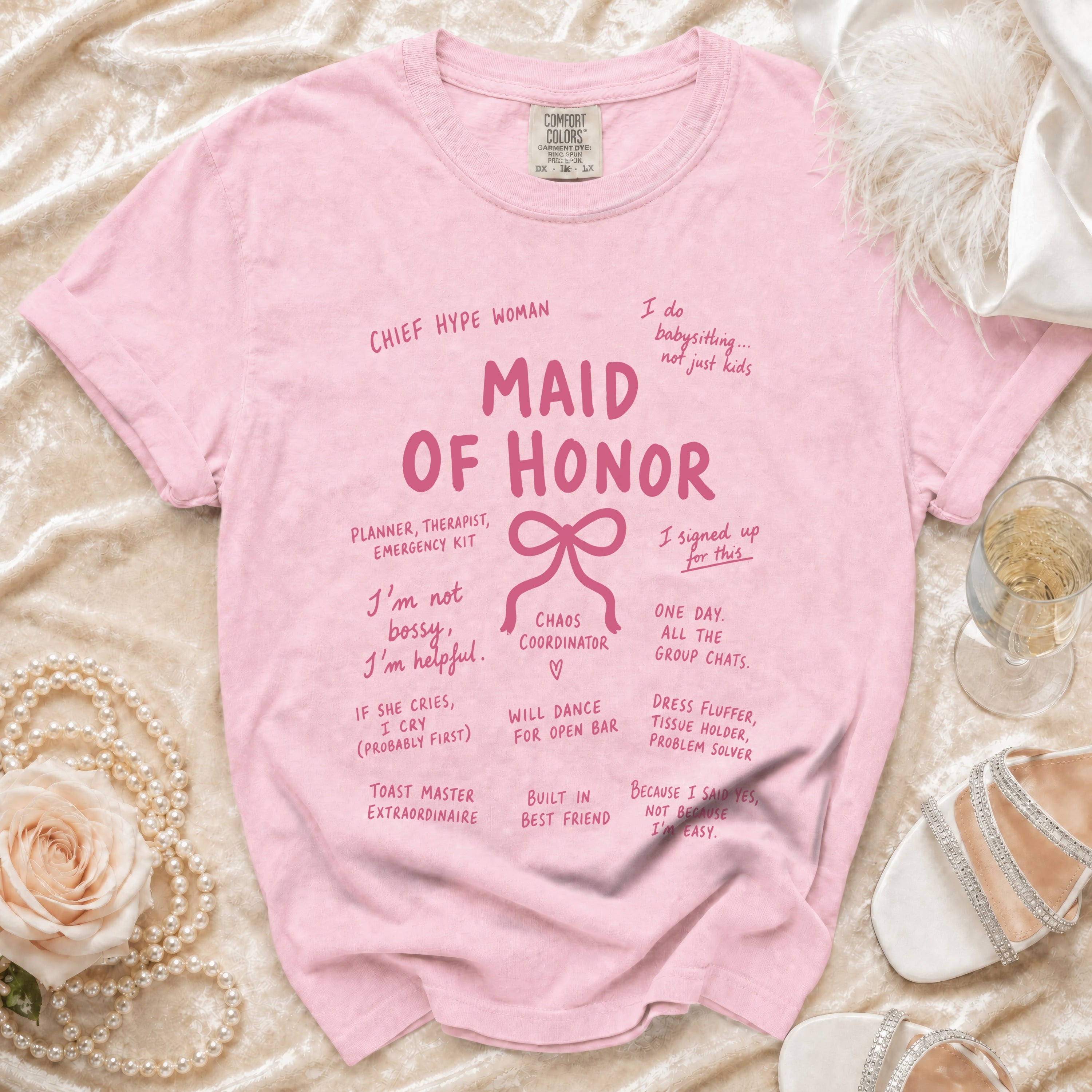 Pink "Maid of Honor" t-shirt with humorous wedding party roles printed on the front.