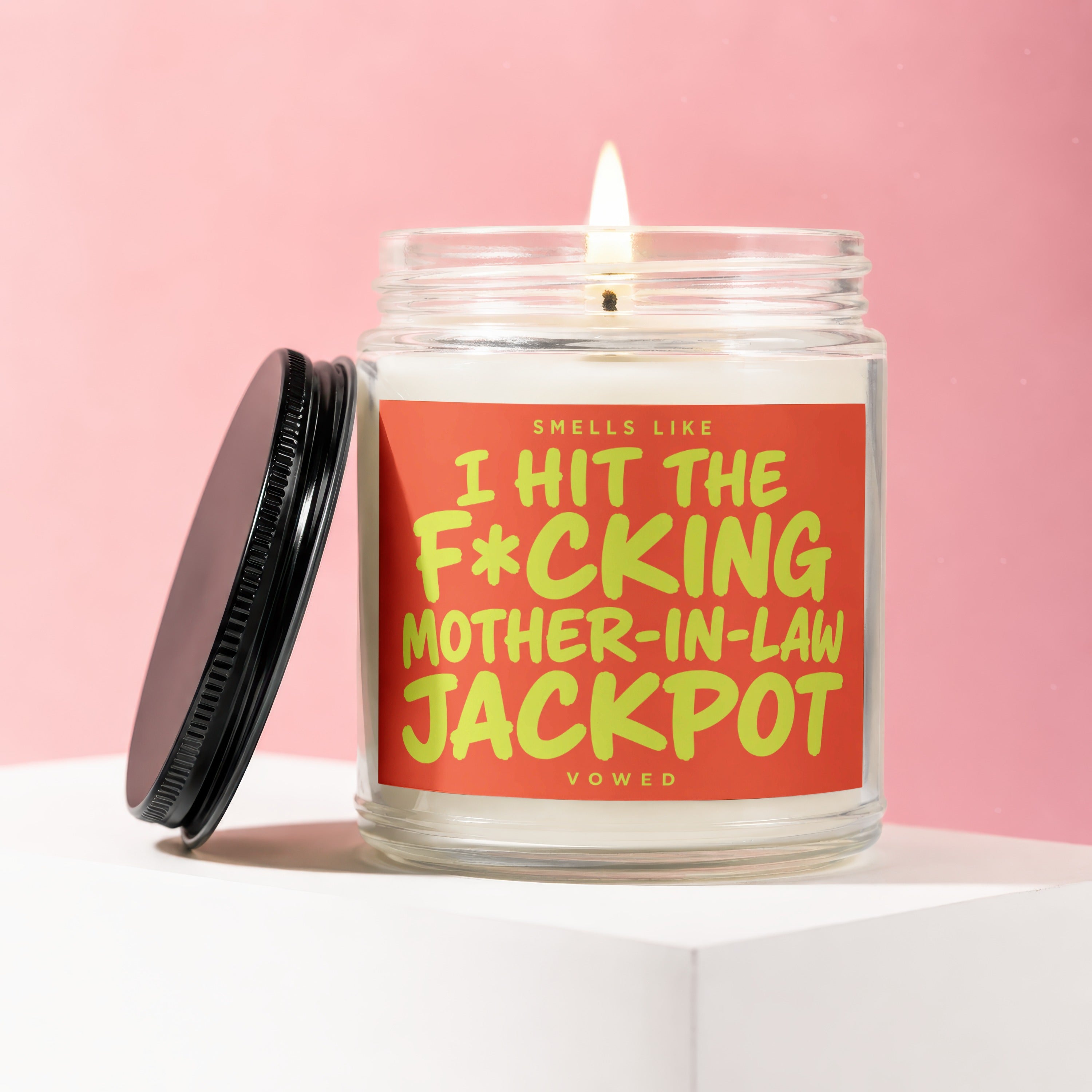 Lit candle in jar with black lid, reads "Smells like I hit the mother-in-law jackpot."