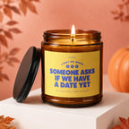 Amber candle with yellow label reading "Light me when someone asks if we have a date yet."