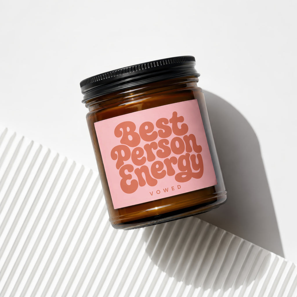 Brown glass candle in jar with pink label reading "Best Person Energy".