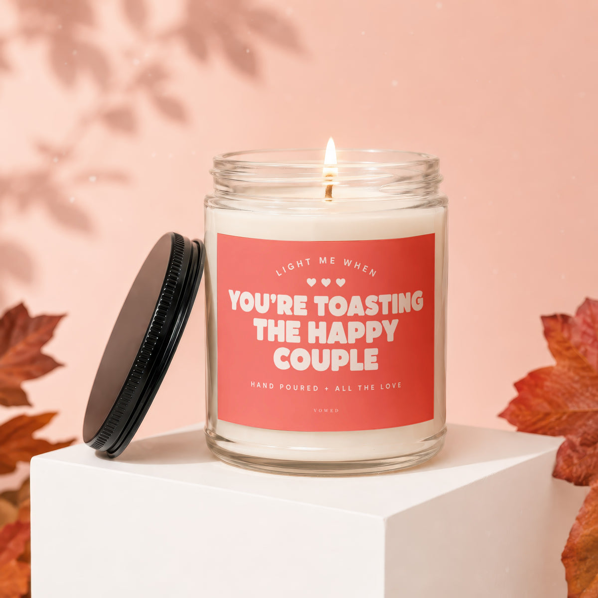 Candle with text "Light me when you're toasting the happy couple" on a pink background.