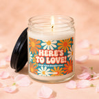 Candle with text "HERE'S TO LOVE! FROM YOUR BIGGEST FANS" and floral design.