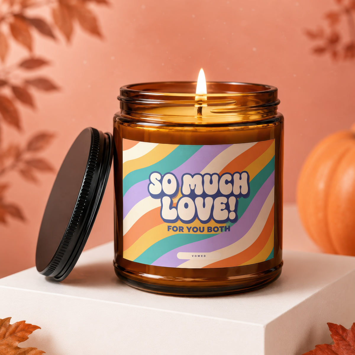 Amber jar candle with a lit wick and a label that reads "SO MUCH LOVE! FOR YOU BOTH VOWED".