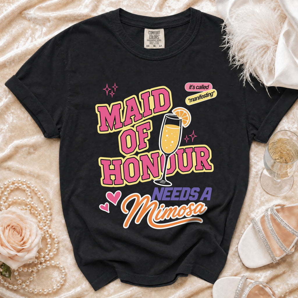 Black t-shirt with "Maid of Honour Needs a Mimosa" text and champagne glass graphic.