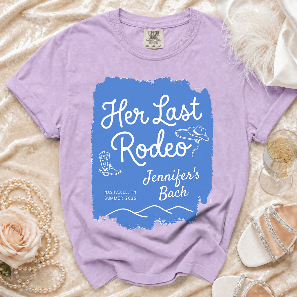 Lavender t-shirt with "Her Last Rodeo Jennifer's Bach" text, cowboy boots, and hat.
