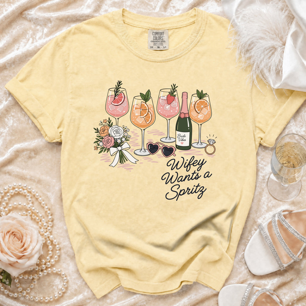 Yellow t-shirt with "Wifey Wants a Spritz" text and illustrations of drinks, flowers, and accessories.