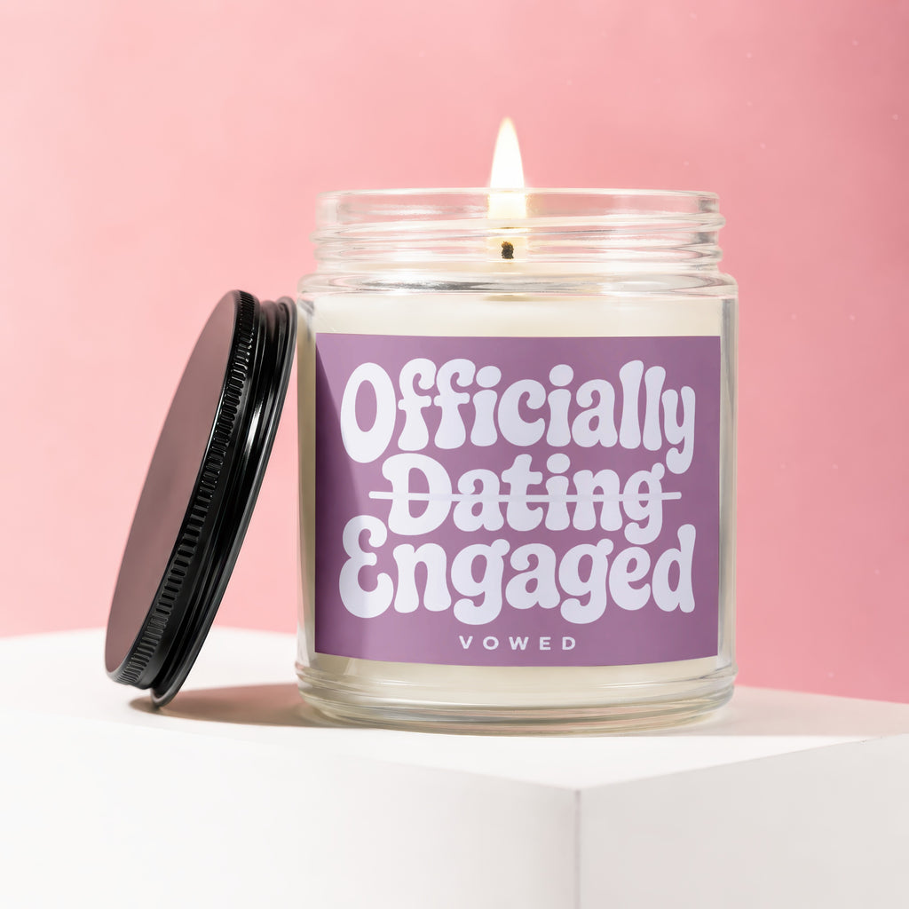 Burning candle in glass jar with "Officially Dating Engaged Vowed" label.