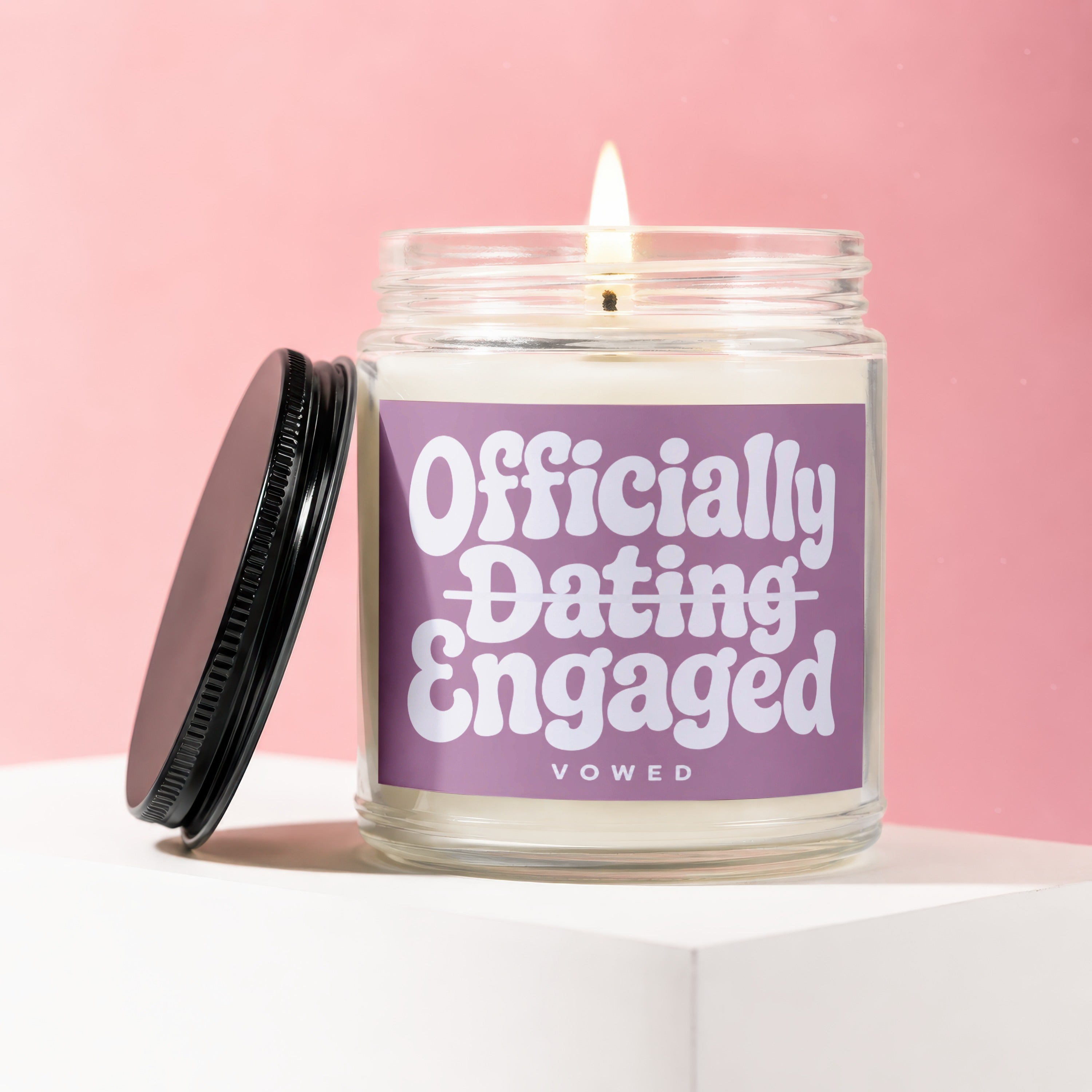 Burning candle in glass jar with "Officially Dating Engaged Vowed" label.