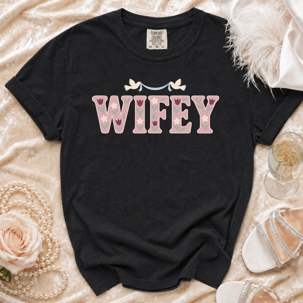 Black t-shirt with pink "WIFEY" text and floral details, two doves above.