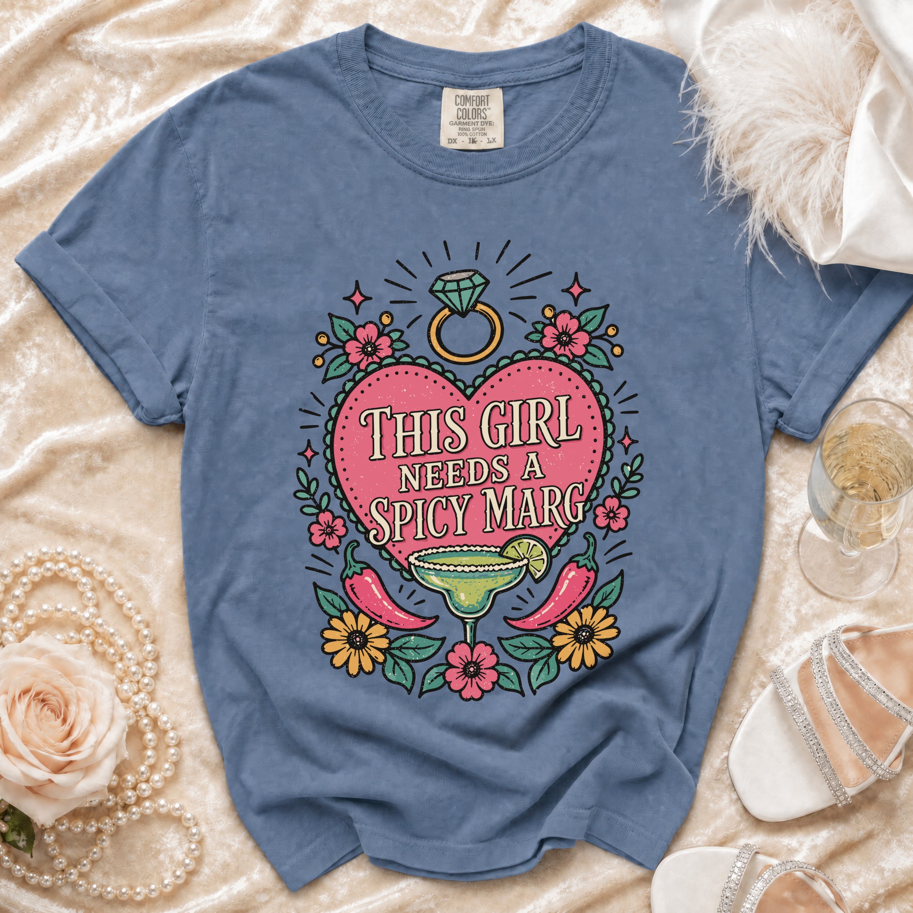 Blue t-shirt with a heart graphic reading "This Girl Needs A Spicy Marg".
