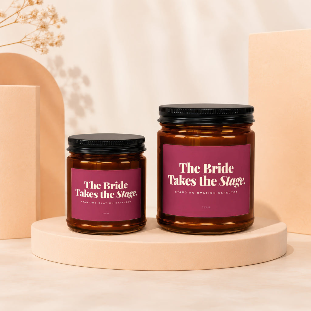 Two amber glass candles with black lids labeled "The Bride Takes the Stage".