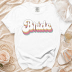 White t-shirt with "Bride" in stacked, retro-style lettering and wedding accessories.