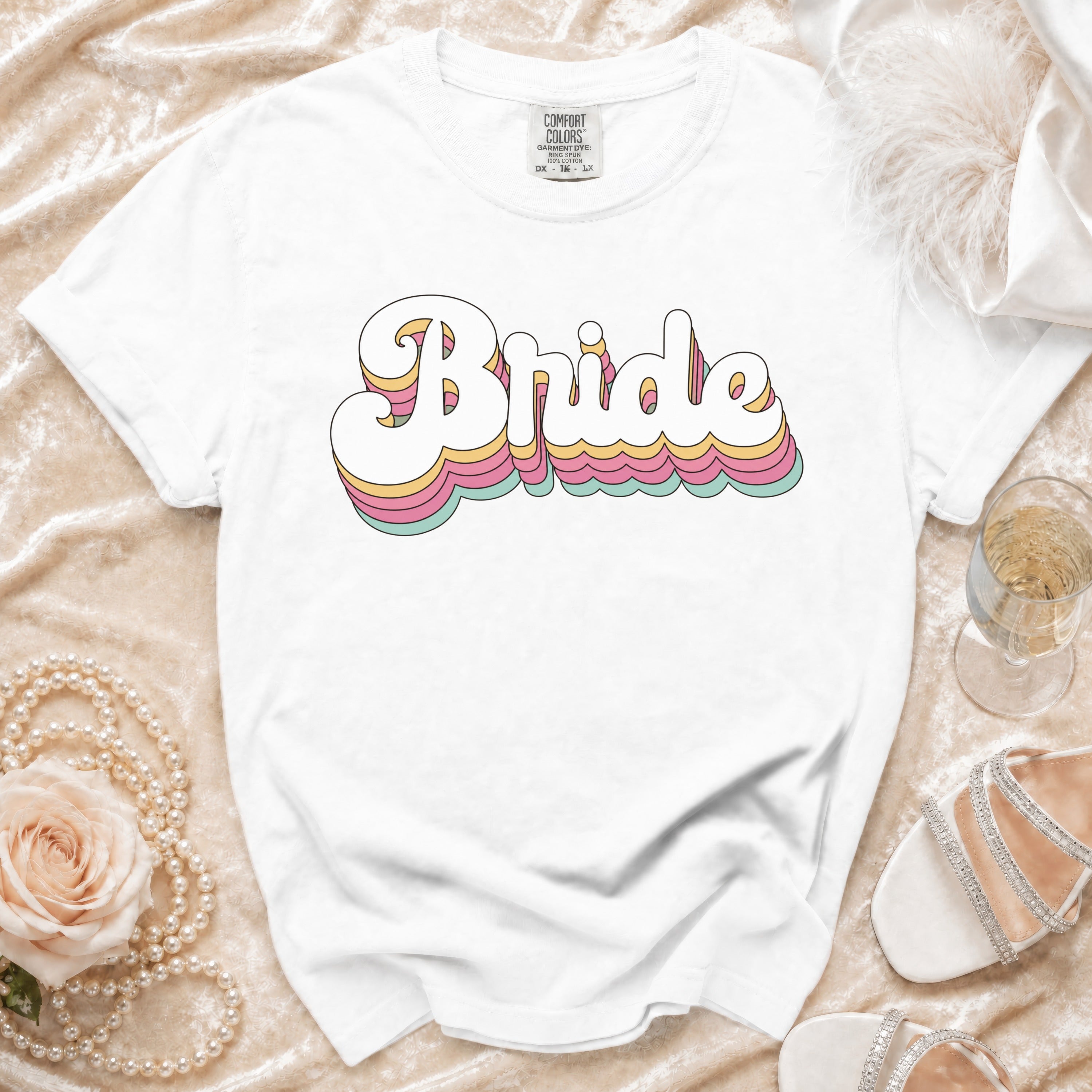 White t-shirt with "Bride" in stacked, retro-style lettering and wedding accessories.