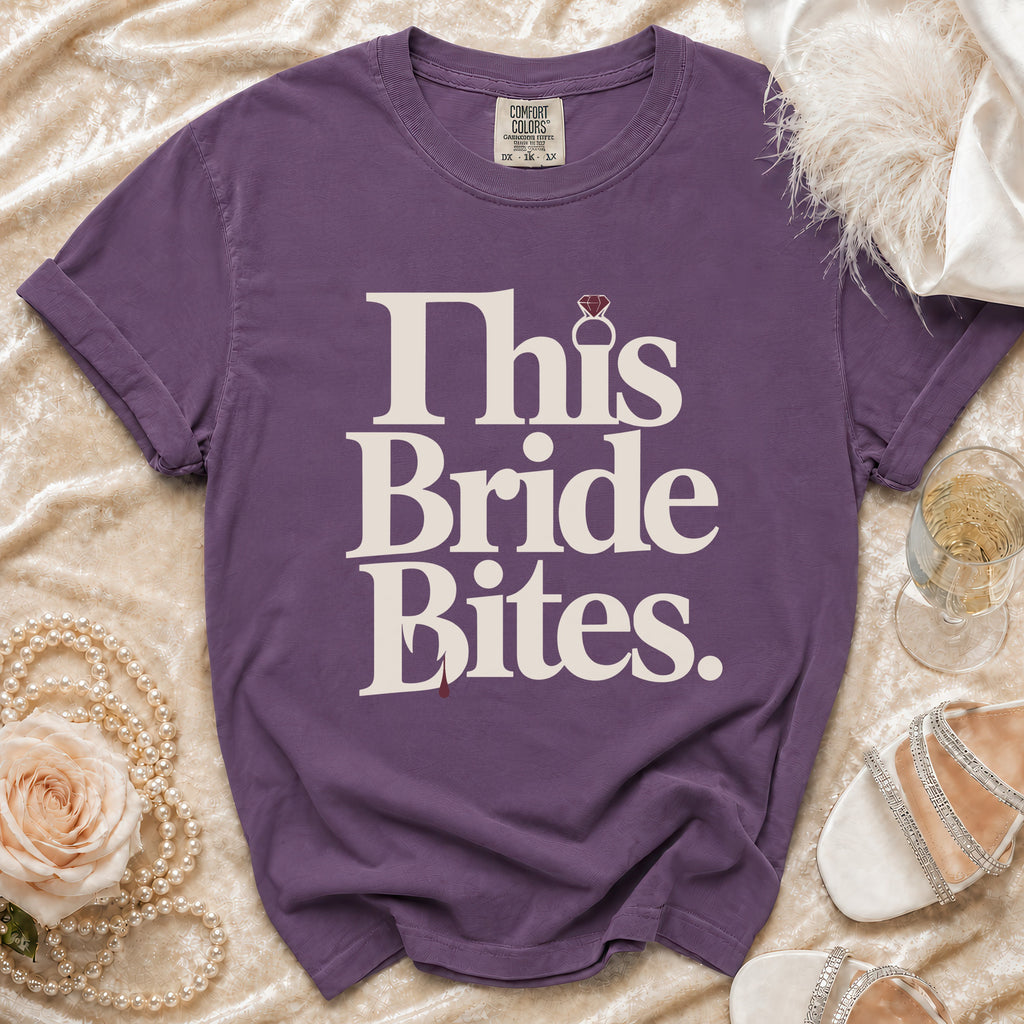 Purple t-shirt with "This Bride Bites." text and diamond ring graphic.