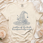 Beige t-shirt with navy print of witch hat, rose, spider, and text "mother of the bride & professionally wicked".